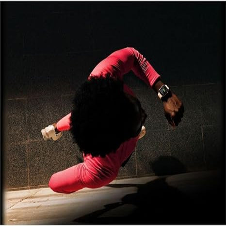 Person in red outfit performing a handstand on a dark tiled floor.